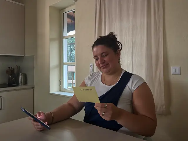 Mulher com o braço na tipoia lendo uma mensagem no celular em casa